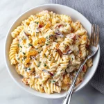 A large bowl of creamy pasta salad with rotini pasta, cherry tomatoes, cucumbers, red onion, and a creamy dressing.
