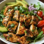Close-up of a colorful keto chicken salad featuring greens, avocado, and cherry tomatoes.