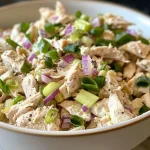 Close-up of a classic chicken salad in a bowl, showcasing diced chicken, celery, and red onion.