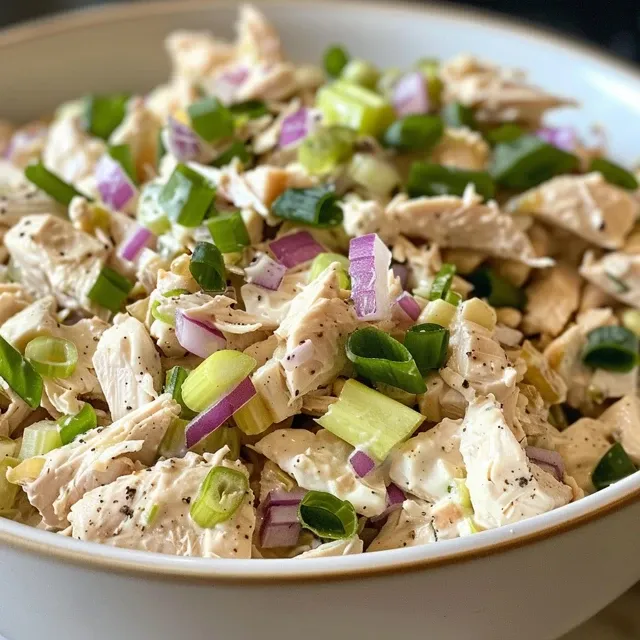 Close-up of a classic chicken salad in a bowl, showcasing diced chicken, celery, and red onion.
