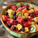 A colorful array of fresh fruits including watermelon, grapes, kiwi, pineapple, strawberries, blueberries, blackberries, and pomegranate seeds in a bowl.
