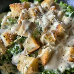 Close-up view of creamy Healthy Caesar Dressing in a bowl with fresh ingredients nearby.