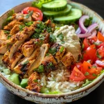 A close-up view of a Chicken Shawarma Bowl featuring juicy chicken, fresh vegetables, and rice.