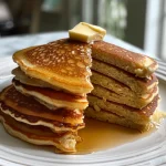 Close-up view of golden-brown gluten-free almond flour pancakes stacked on a plate.
