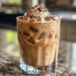 Close-up of a delicious iced mocha oat latte with chocolate shavings and whipped cream.