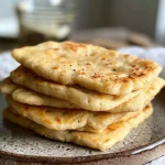 A close-up side view of freshly cooked vegan chickpea flour flatbreads on a plate.