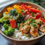 A close-up view of a vibrant Lunch Box Rice and Chicken Bowl, showcasing juicy chicken and colorful vegetables.