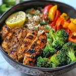 Close-up of a colorful chicken and veggie power bowl featuring sliced chicken, vibrant vegetables, and fluffy rice.