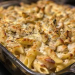 Close-up view of a slice of Chicken Alfredo Casserole on a plate, showcasing creamy sauce and chicken.