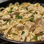 A close-up view of creamy Chicken Alfredo Pasta with fettuccine and garnished with parsley.
