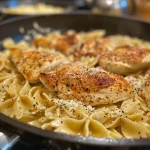 A close-up side view of a creamy Chicken Garlic Parmesan Pasta dish topped with grated parmesan cheese.