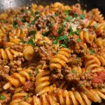 Close-up view of creamy beef pasta topped with grated cheese and fresh parsley.