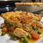 Close-up view of a golden-brown chicken pot pie with visible steam.