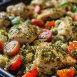 A close-up view of pesto chicken served over cauliflower rice with cherry tomatoes.