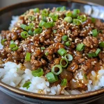 Juicy teriyaki ground beef garnished with sesame seeds and sliced green onions.