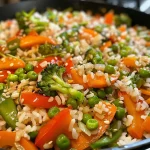 A colorful bowl of veggie stir-fry rice featuring bell peppers, carrots, snow peas, and broccoli.