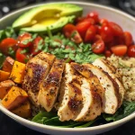 A vibrant chicken quinoa power bowl with colorful vegetables and avocado.