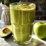 Close-up side view of a green smoothie with avocado and green apple.