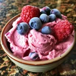 Close-up side view of creamy berry frozen yogurt with vibrant berries on top.