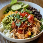 Close-up view of a colorful Crockpot Salsa Chicken Burrito Bowl with various toppings.