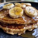 Close-up view of golden-brown banana oat pancakes stacked on a plate.