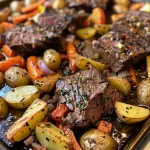 Close-up view of a juicy sheet pan beef and vegetable dish, showcasing tender beef chunks, colorful bell peppers, and golden roasted potatoes.