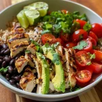 A close-up of a colorful chicken burrito bowl with grilled chicken, black beans, and fresh vegetables.