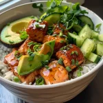 A close-up side view of a honey glazed salmon bowl with colorful ingredients.