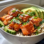 A close-up view of honey glazed salmon rice bowls featuring salmon cubes, brown rice, and fresh vegetables.