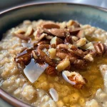 A close-up view of a bowl of honey nut oatmeal topped with chopped nuts.