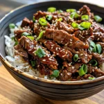 A close-up view of a bowl filled with Korean BBQ beef topped with green onions and sesame seeds.