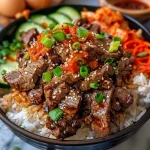 A close-up view of a Korean BBQ Beef Rice Stack with colorful vegetables and a fried egg on top.