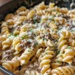 Close-up view of creamy beef and garlic butter pasta in a bowl, garnished with herbs.
