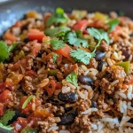 Close-up view of a skillet filled with smoky honey chili beef rice, garnished with cilantro.