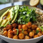 Close-up of a spicy roasted chickpea and avocado bowl with quinoa, topped with lemon dressing.