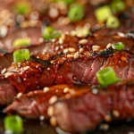 Close-up view of a juicy honey garlic flank steak on a plate.