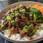 Close-up view of a vibrant Asian Beef Bowl topped with green onions and sesame seeds.