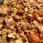 Close-up view of crunchy vanilla almond granola with visible almonds and oats.