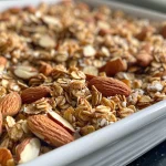 Close-up view of a bowl filled with vanilla almond granola topped with almonds and chia seeds.