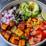 Close-up view of a colorful vegan sweet potato burrito bowl filled with diced sweet potatoes, black beans, and fresh vegetables.