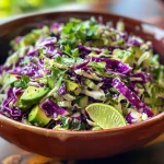 ['A close-up side view of vibrant avocado cabbage slaw in a bowl.', 'A detailed image of fresh avocado cabbage slaw with visible chunks of avocado and green cabbage.', 'Side view of a colorful avocado cabbage slaw featuring diced cucumber and cilantro.', 'Juicy avocado cabbage slaw displayed with bright lime accents and fresh ingredients.']
