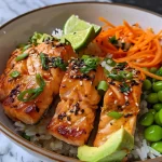['Close-up of a colorful salmon rice bowl topped with sliced avocado, cucumber, and carrots.', 'High-protein salmon rice bowl featuring cubed salmon, jasmine rice, and vibrant vegetables.', 'Side view of a nutritious salmon rice bowl with toppings including edamame and sesame seeds.', 'Juicy salmon rice bowl garnished with green onions and lime wedges on the side.']