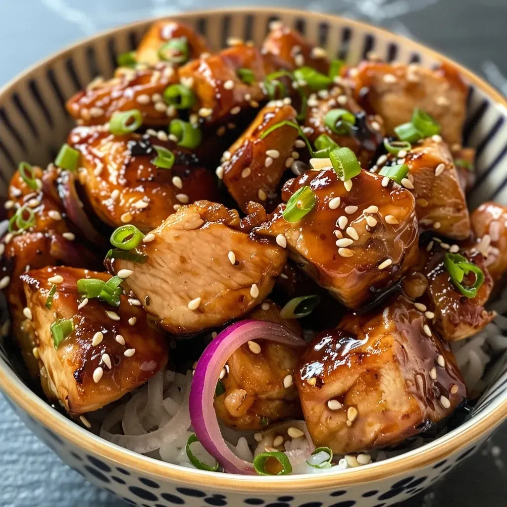 ['Juicy teriyaki chicken thighs garnished with sesame seeds on a plate.', 'Close-up of a delicious keto teriyaki chicken dish with red onion slices.', 'Succulent diced chicken glazed with teriyaki sauce, served with sesame seeds.', 'Side view of tender keto teriyaki chicken, showcasing glistening sauce and garnishes.']