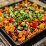 ['Close-up of a colorful Smoky Sweet Potato and Black Bean Salad with fresh ingredients.', 'Vibrant salad featuring cubed sweet potatoes, black beans, and diced vegetables.', 'Detailed view of a healthy, hearty salad highlighting the textures and colors of its ingredients.', 'Artistic side view of Smoky Sweet Potato and Black Bean Salad, showcasing its fresh and vibrant appeal.']