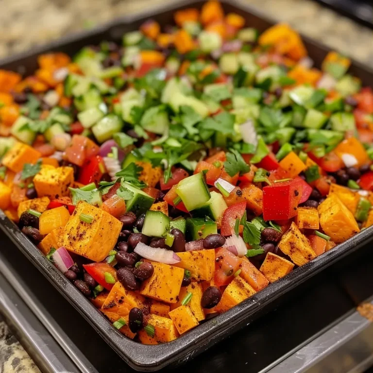 ['Close-up of a colorful Smoky Sweet Potato and Black Bean Salad with fresh ingredients.', 'Vibrant salad featuring cubed sweet potatoes, black beans, and diced vegetables.', 'Detailed view of a healthy, hearty salad highlighting the textures and colors of its ingredients.', 'Artistic side view of Smoky Sweet Potato and Black Bean Salad, showcasing its fresh and vibrant appeal.']