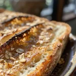 ['Close-up view of a slice of Apple Crisp Artisan Sourdough Bread, revealing its golden crust and apple pieces.', 'Side view of a loaf of Apple Crisp Artisan Sourdough Bread, showcasing its textured surface and artisanal quality.', 'Detailed shot of Apple Crisp Artisan Sourdough Bread, highlighting the crispy crust and visible apple bits.', 'An inviting slice of Apple Crisp Artisan Sourdough Bread, displaying its fluffy interior and rich color.']