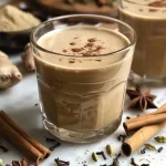 ['Close-up view of a glass of Chai Concentrate with spices sprinkled around it.', 'Side view of a creamy Chai Concentrate featuring a rich brown color and various spices.', 'Delicious Chai Concentrate in a clear glass, highlighting its thick consistency and spices.', 'Detailed side shot of Chai Concentrate showcasing its texture and vibrant color.']