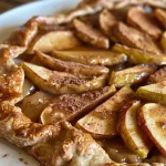 ['Close-up side view of a baked Cinnamon Apple Galette with golden crust and juicy apple filling.', 'A rustic Cinnamon Apple Galette displaying slices of Granny Smith apples and a flaky pastry edge.', 'Side angle of a deliciously baked Cinnamon Apple Galette with caramelized apples and cinnamon dust.', 'Detailed view of a Cinnamon Apple Galette showcasing its golden crust and vibrant apple slices.']