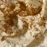 ['Creamy cinnamon cheesecake dip in a bowl, garnished with a sprinkle of cinnamon.', 'Close-up view of a rich cinnamon cheesecake dip with a smooth texture.', 'Bowl of cinnamon cheesecake dip with cream cheese visible and a buttery sheen.', 'Side view of a decadent cinnamon cheesecake dip showcasing its creamy consistency.']