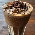 ['Close-up side view of a creamy coffee milkshake topped with whipped cream and chocolate shavings.', 'Frothy coffee milkshake in a glass, showcasing a rich chocolate drizzle and whipped cream.', 'Thick coffee milkshake captured from the side, adorned with fudge sauce and a sprinkle of cocoa.', 'Appetizing side view of a coffee-flavored milkshake, featuring a swirl of chocolate and whipped cream on top.']